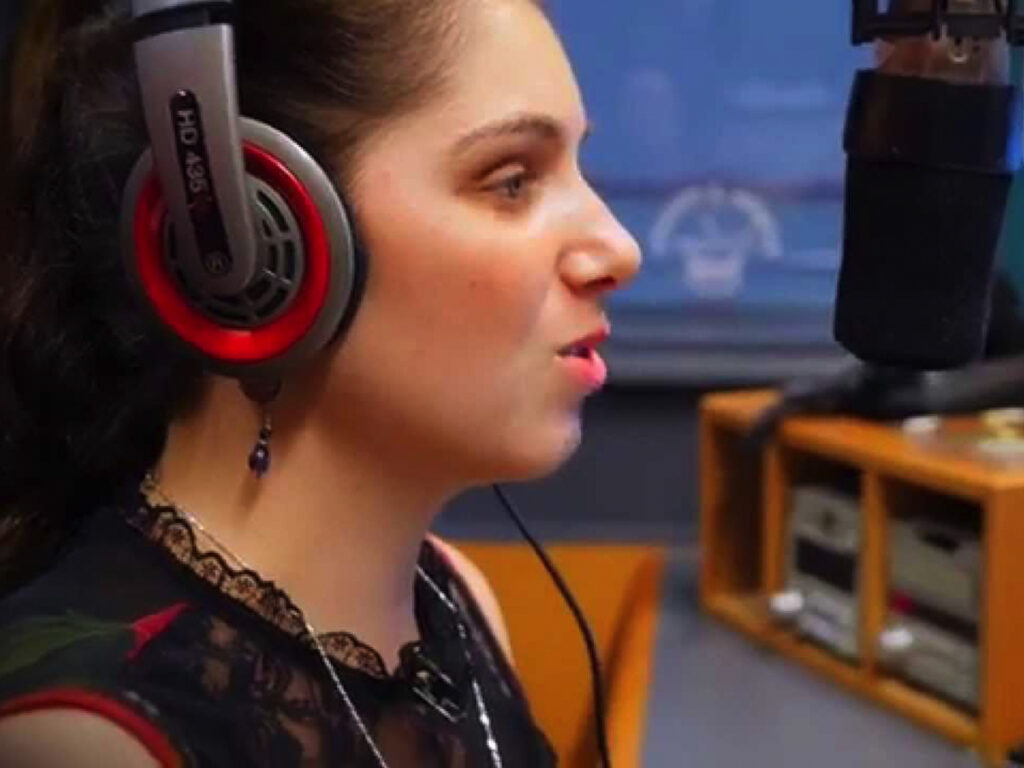 Nas Campanella wearing headphones talking into a microphone while doing a radio broadcast